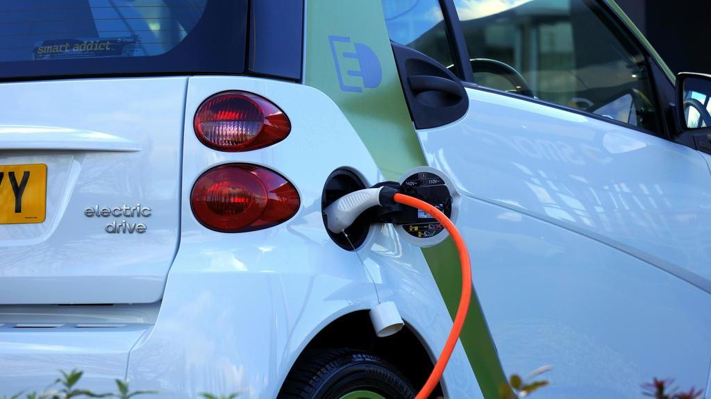alt_text: Na tle miasta stoją nowoczesne electric cars.